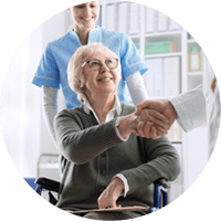 Doctor giving an handshake to a smiling senior female patient and caring nurse, healthcare and trust concept